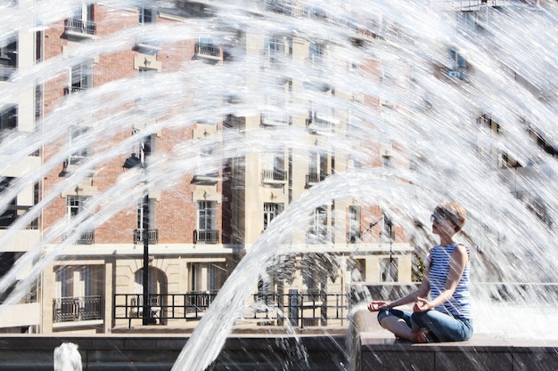 La jeune femme échappe à la vague de chaleur dans la fontaine de la ville