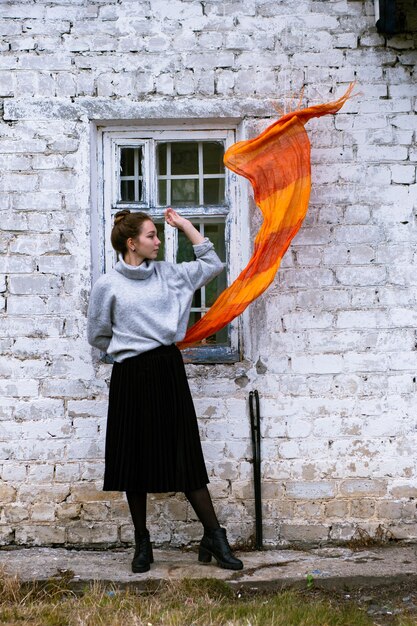 Jeune femme avec une écharpe orange sur le vieux mur de briques blanches en arrière-plan