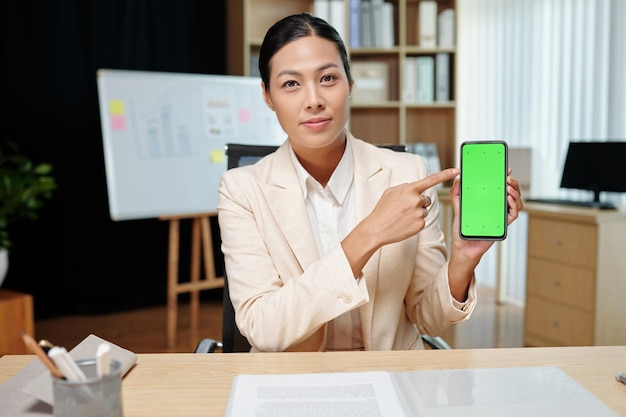 Jeune femme économiste confiante pointant sur l'écran vert du smartphone