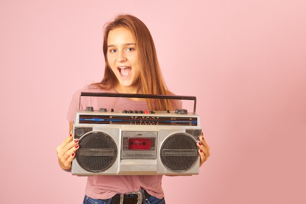 Jeune femme écoutant de la musique avec cassette radio vintage