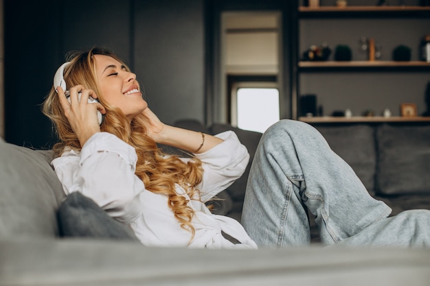 Jeune femme écoutant de la musique dans des écouteurs dans son appartement