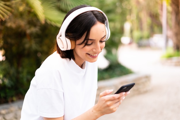 Jeune femme écoutant de la musique à l'extérieur