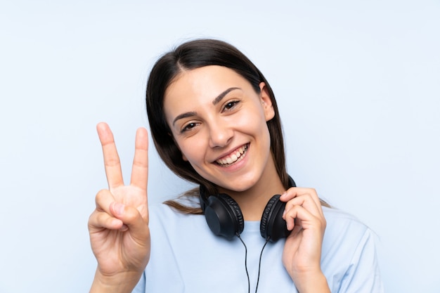 Jeune femme écoutant de la musique sur un mur bleu isolé