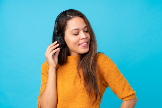 Jeune femme écoutant de la musique sur le mur bleu