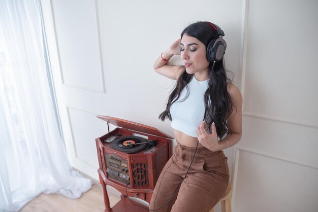 Jeune femme écoutant de la musique avec une platine vintage dans le salon