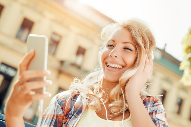 Jeune femme écoutant de la musique sur un téléphone intelligent. Elle écoute de la musique sur un téléphone intelligent dans la ville.