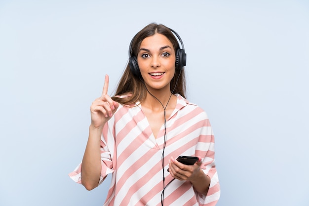 Jeune femme écoutant de la musique avec un téléphone portable pointant vers le haut une excellente idée