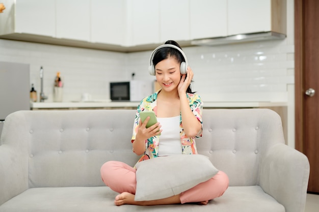 Jeune femme écoutant de la musique tout en vous relaxant sur le canapé à la maison