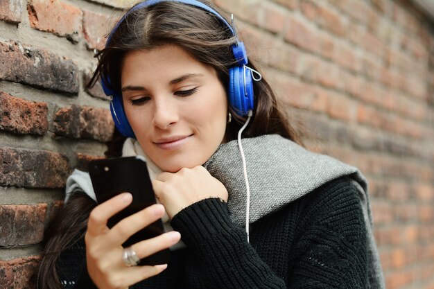 Jeune femme écoutant de la musique et utilisant son smartphone.