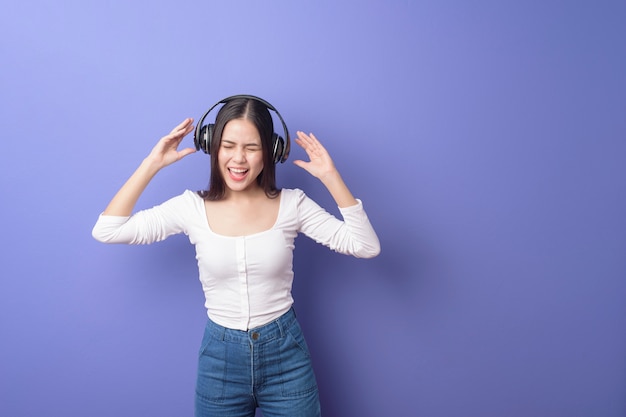 Jeune femme écoute de la musique sur fond violet