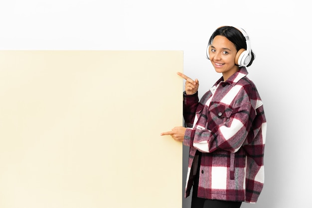 Jeune Femme à L'écoute De La Musique Avec Une Grande Pancarte Vide Sur Fond Isolé Doigt Pointé Sur Le Côté Et Présentant Un Produit