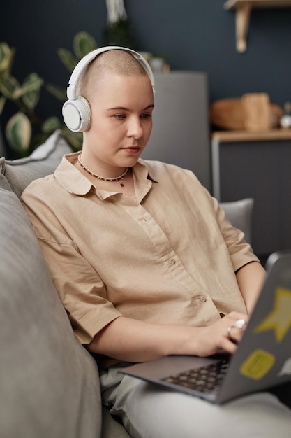 Une jeune femme avec des écouteurs tapant sur un ordinateur portable