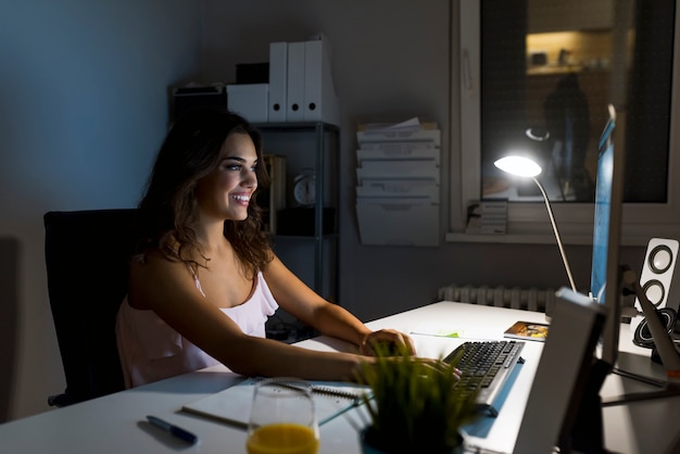 Une jeune femme écrivant alors qu&#39;elle était assise dans son bureau la nuit