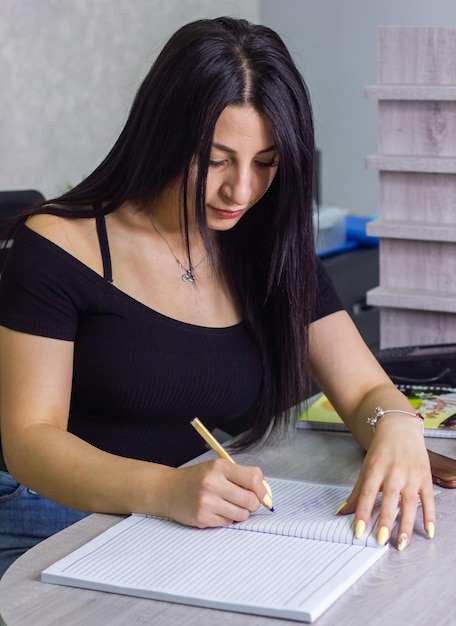 Photo une jeune femme écrivant sur un cahier dans son bureau