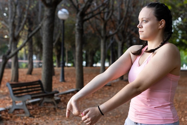 Jeune femme effectuant des étirements de biceps après avoir fait du sport en automne dans la rue