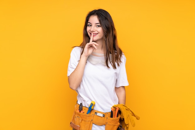 Jeune femme électricien sur isolé sur jaune faisant le geste de silence