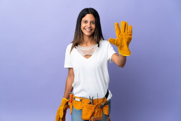 Jeune femme électricienne isolée sur mur violet comptant cinq avec les doigts