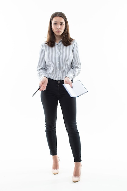 Jeune femme élégamment habillée avec un cahier sur fond blanc Un employé de bureau pose dans le studio