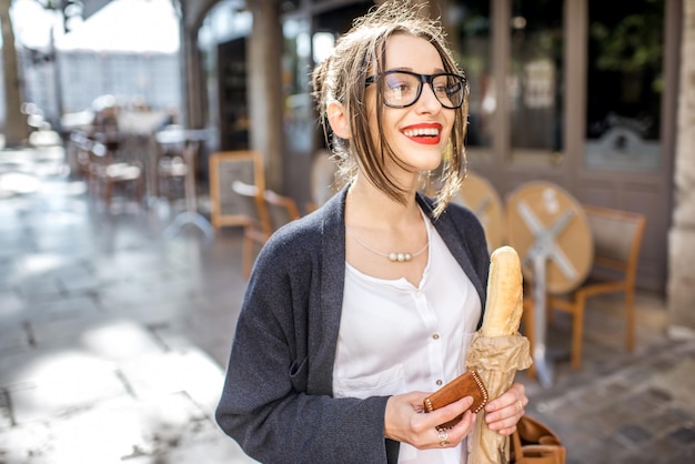 Jeune femme élégante achetant une baguette française debout dans la rue dans la ville de Lyon