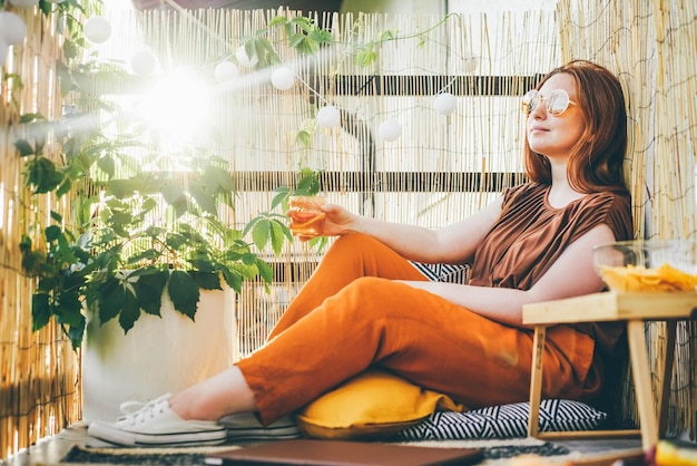 Photo une jeune femme élégante assise et tenant un cocktail sur une terrasse moderne