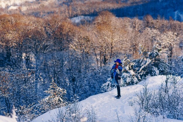 Jeune femme élégante au chapeau bleu et gants rouges marchant dans le parc