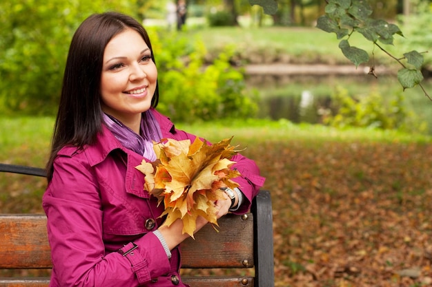 Jeune femme élégante aux feuilles d'automne