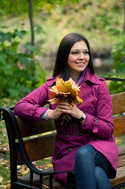 Jeune femme élégante aux feuilles d'automne