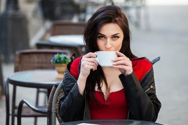 Jeune femme élégante, boire du café dans une rue de la ville.