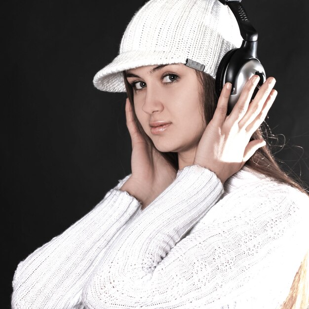 Photo jeune femme élégante écoutant de la musique avec un casque .isolé sur fond noir.