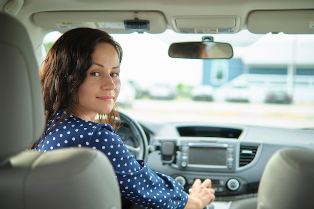 Jeune femme élégante pilote assis derrière le volant de sa voiture Concept de véhicule de conduite