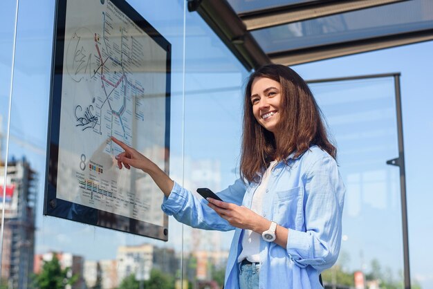 Une jeune femme élégante qui attend les transports en commun alors qu'elle se tient à la gare de tramway moderne à l'extérieur