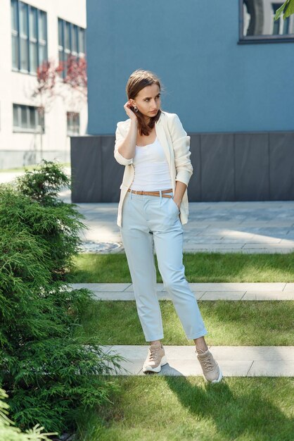 Photo une jeune femme élégante en tenue décontractée se tient près du mur gris du bâtiment moderne