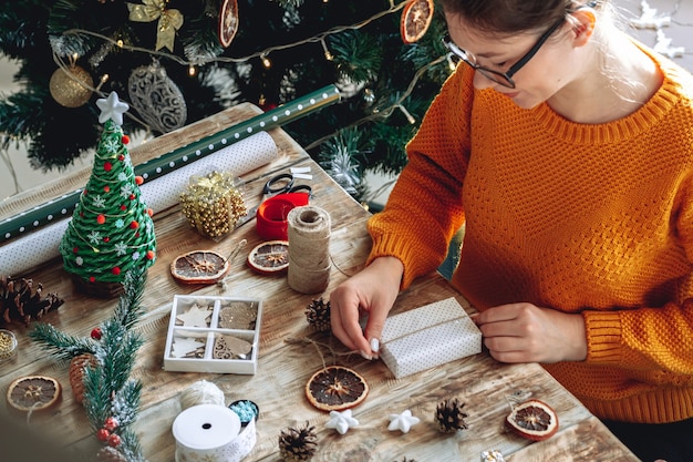 Jeune femme emballage cadeau de Noël sur table