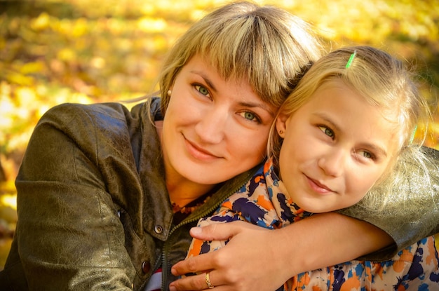 Jeune femme embrassant sa petite fille dans le parc d'automne lumineux