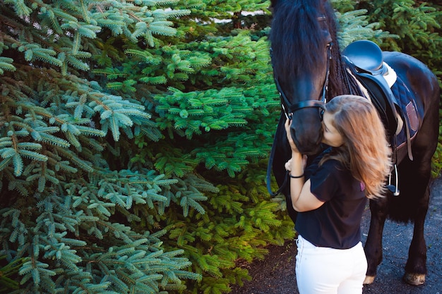 Photo une jeune femme embrasse un cheval alors qu'elle se tient près des arbres.