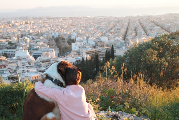 Une jeune femme embrasse son chien alors qu'ils sont assis dans un champ AthènesGrèce vraie lumière chaude du coucher de soleil