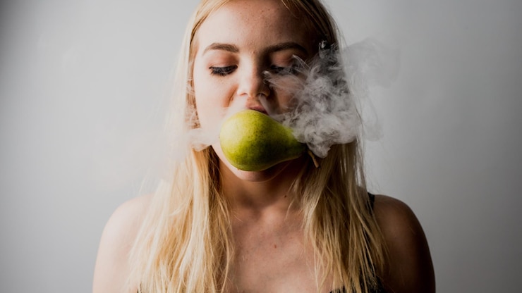 Photo une jeune femme émet de la fumée sur une poire sur un fond blanc