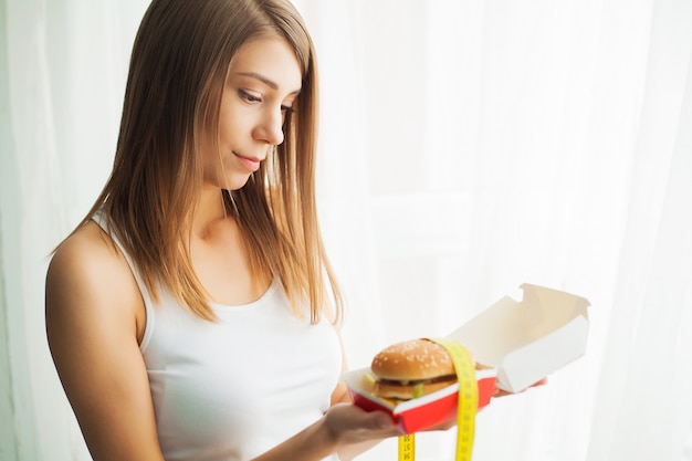 Jeune femme l'empêchant de manger de la malbouffe. Concept d'alimentation saine