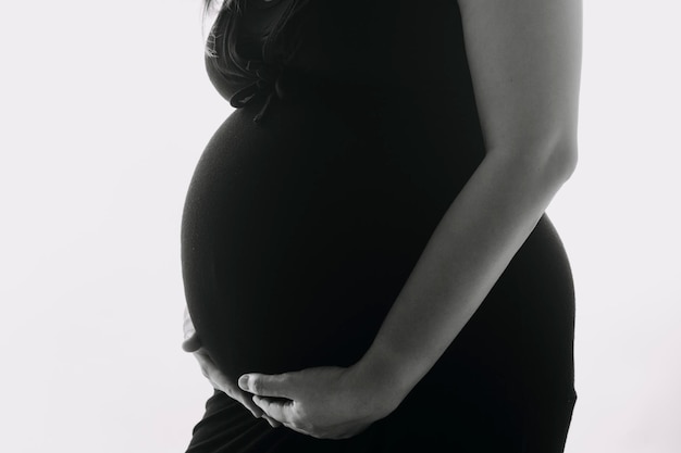 Jeune femme enceinte adulte en vêtements blancs touchant le gros ventre nu avec les mains montrant la forme Concept de grossesse Temps d'attente Gros plan isolé sur fond de mur gris clair