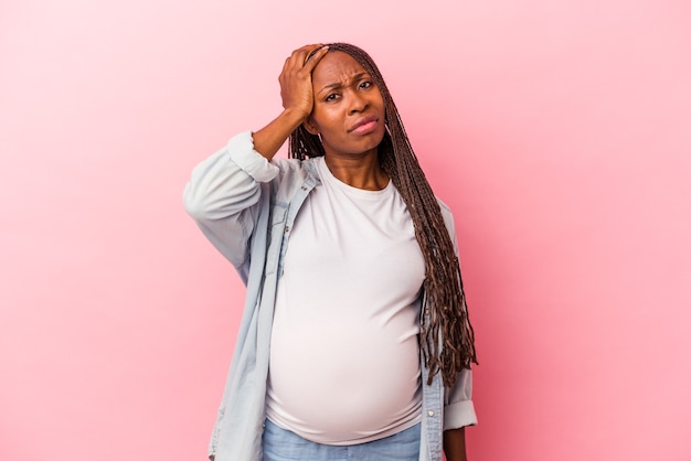 Jeune femme enceinte afro-américaine isolée sur fond rose étant choquée, elle s'est souvenue d'une réunion importante.