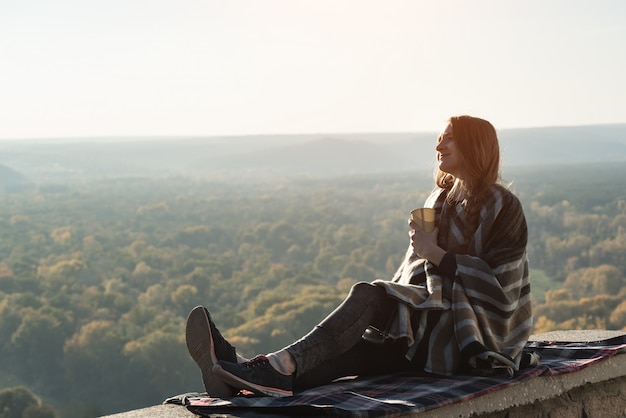 Jeune femme enceinte avec assis sur la colline et regarde au loin.