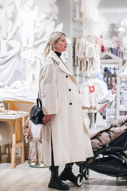 Une jeune femme enceinte choisit des vêtements pour nouveau-nés dans un magasin de baby-shop.