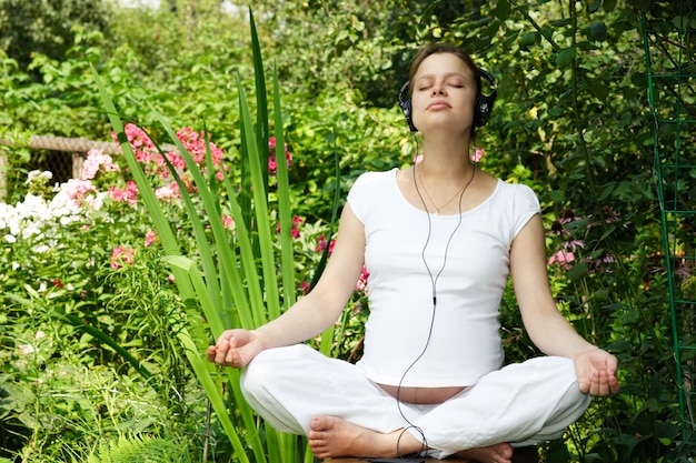 Jeune femme enceinte écoutant de la musique dans un jardin d'été