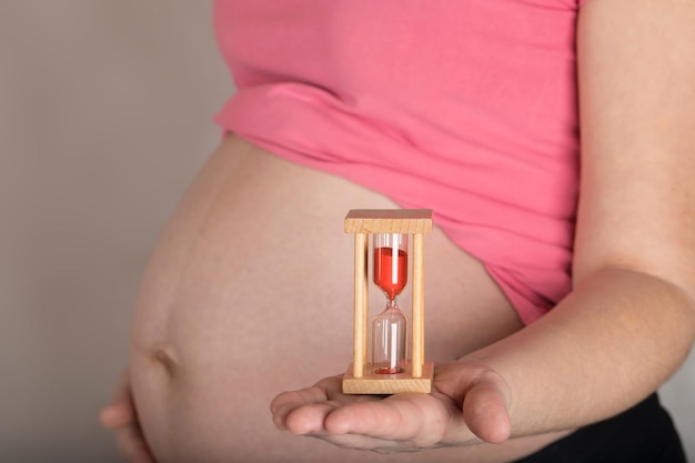 Jeune femme enceinte entre 30 et 35 ans garde sandwatch près de son ventre. Fermer