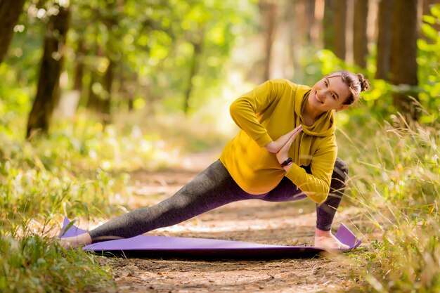 jeune femme enceinte, faire du yoga en été dans la forêt