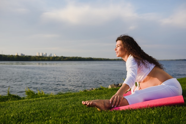 Jeune femme enceinte, faire du yoga en plein air