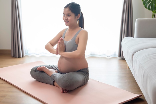 Jeune femme enceinte faisant du yoga à domicile concept de soins de santé et de soins de grossesse