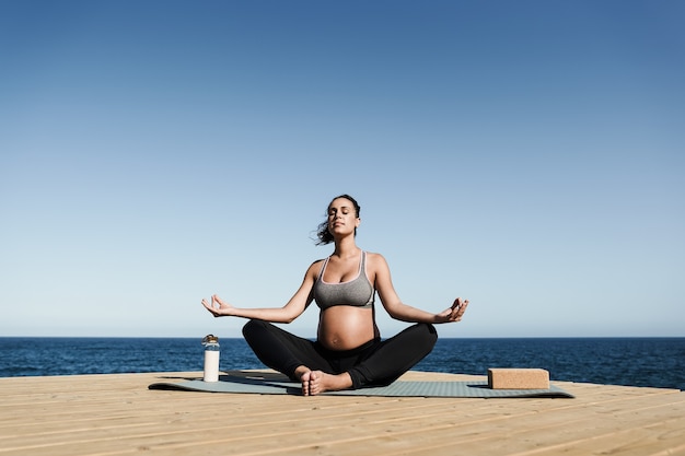 Jeune femme enceinte faisant du yoga méditation en plein air