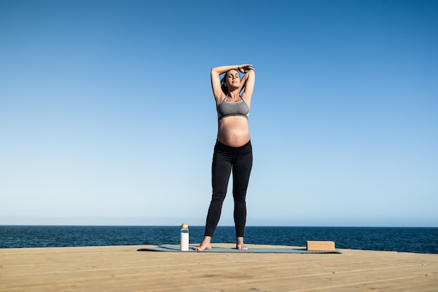 Jeune femme enceinte faisant du yoga en plein air à la plage - Focus on face