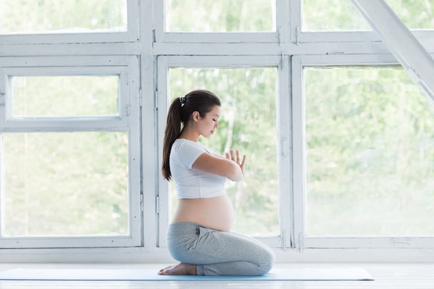 Jeune femme enceinte faisant des exercices de fitness et de yoga